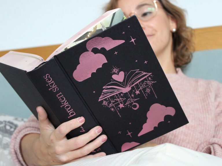 Paket Herzton Frau liest ein schwarzes Buch mit pinkem Cover in einem gemütlichen Raum.