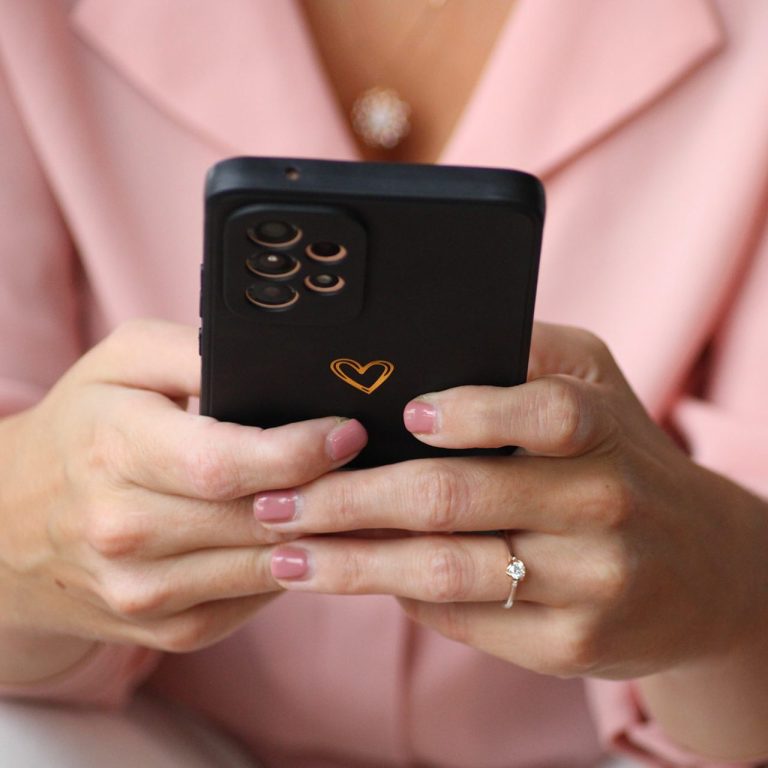 Paket Herzstück Hände einer Person mit einem Smartphone, das ein herzförmiges Symbol zeigt.
