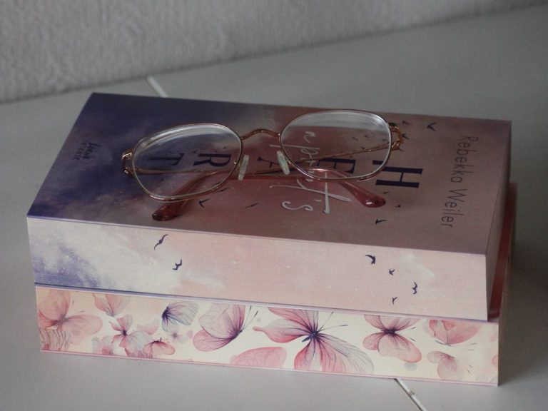 Paket Seelenblick Ein Buch mit einer Brille darauf, dekoriert mit floralen Mustern.
